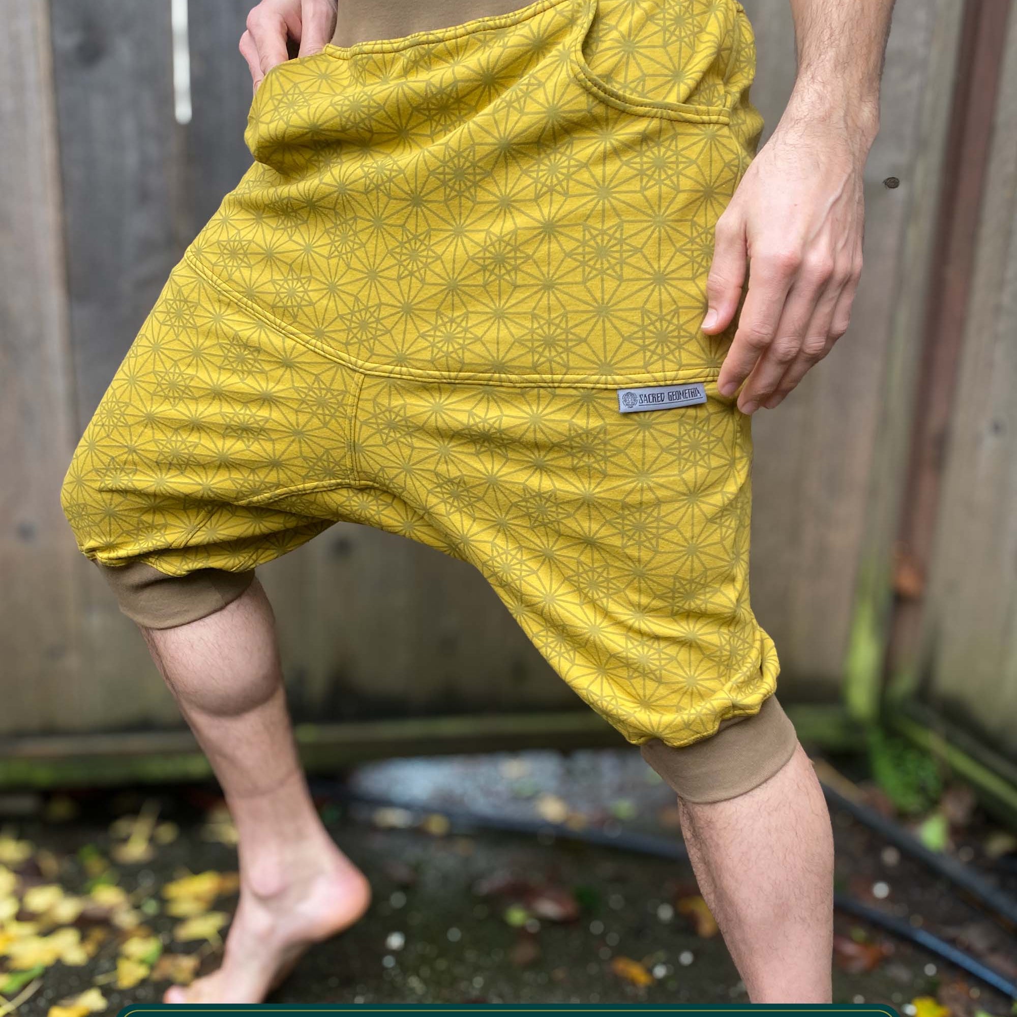 Organic cotton drop crotch shorts, yellow fabric with geometric print, front right side view on male model.