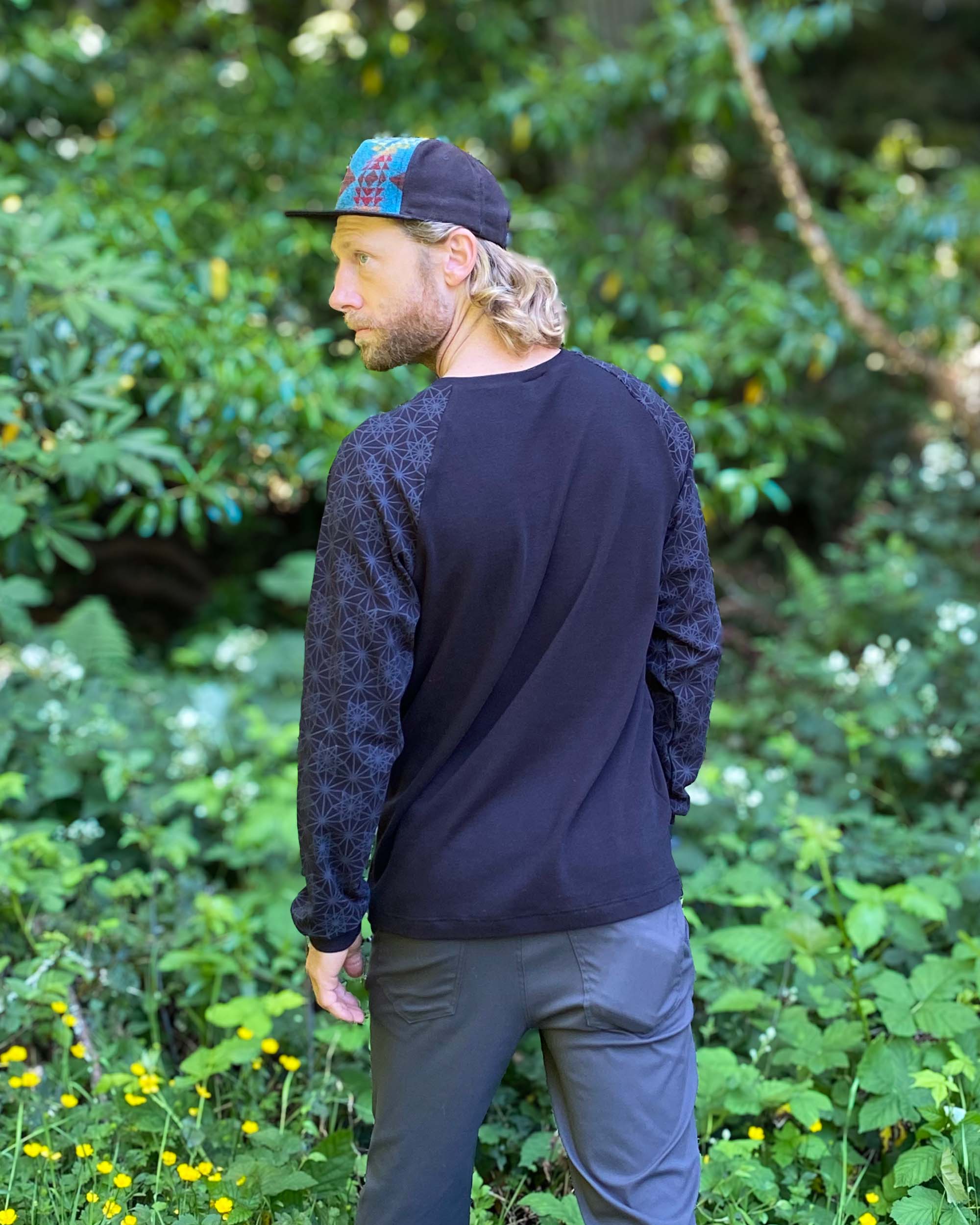 Organic cotton long sleeve shirt, black with geometric sleeve prints, back side view on male model.