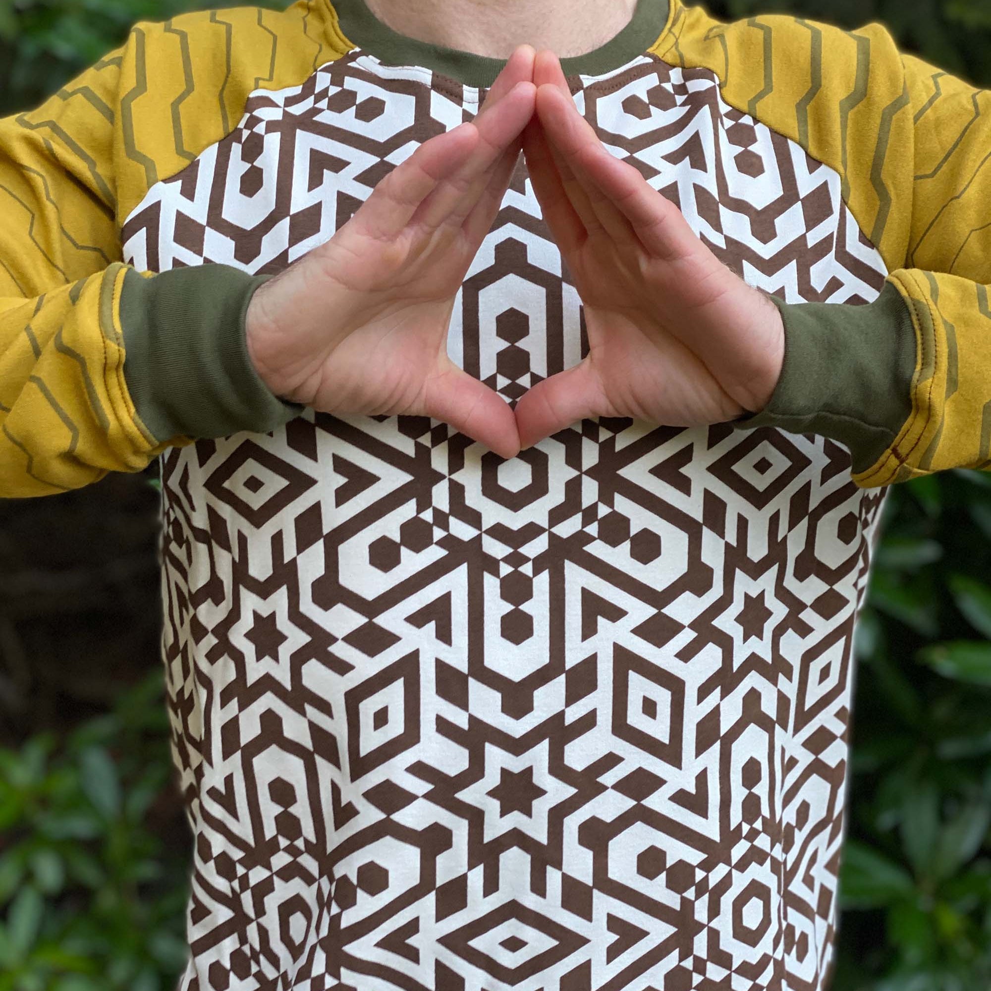 Organic cotton long sleeve shirt, undyed torso fabric with yellow geometric striped sleeves, front detail view of print.