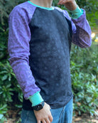 Organic cotton long sleeve shirt, black with lavender geometric sleeves, front right side view on model.
