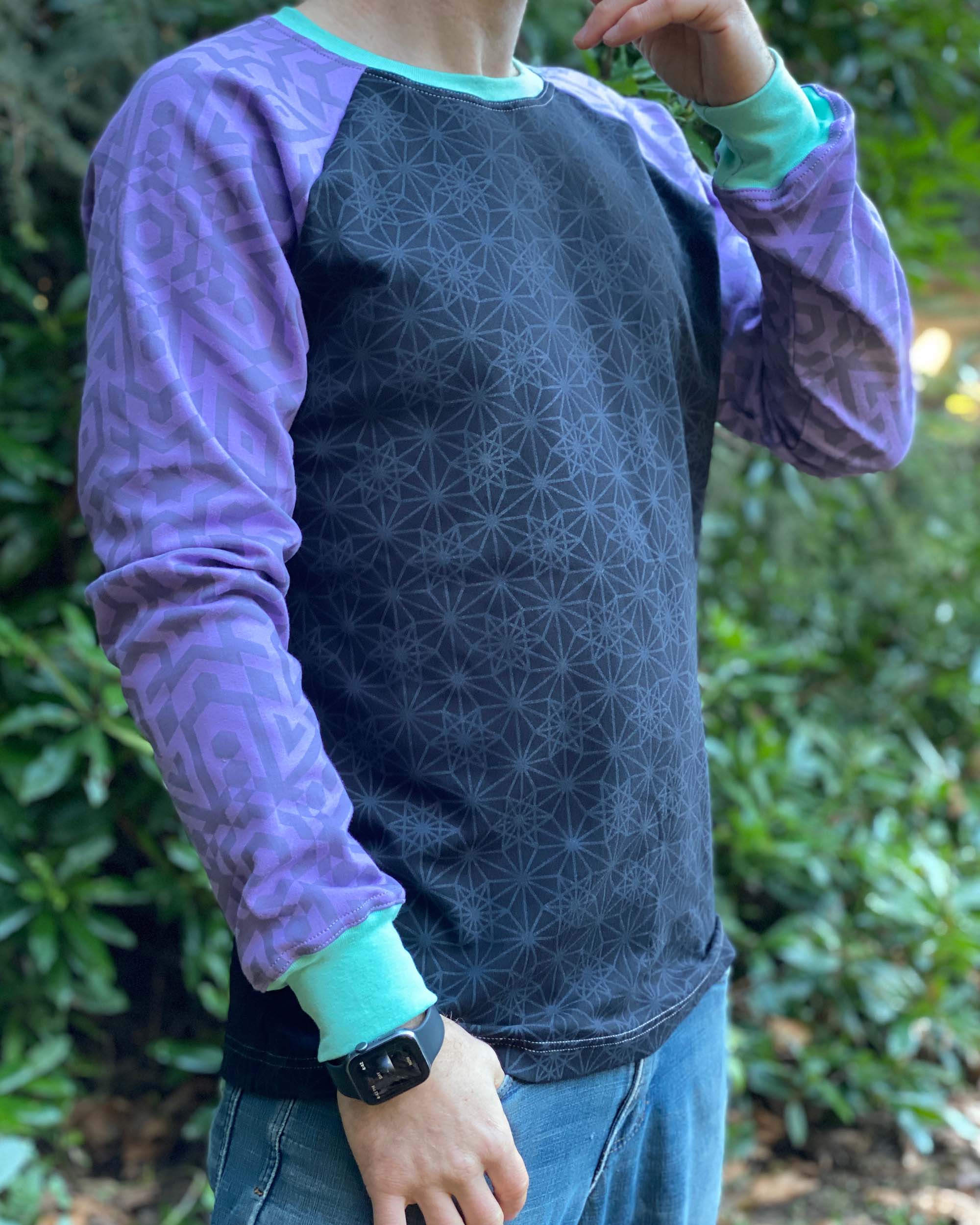 Organic cotton long sleeve shirt, black with lavender geometric sleeves, front right side view on model.