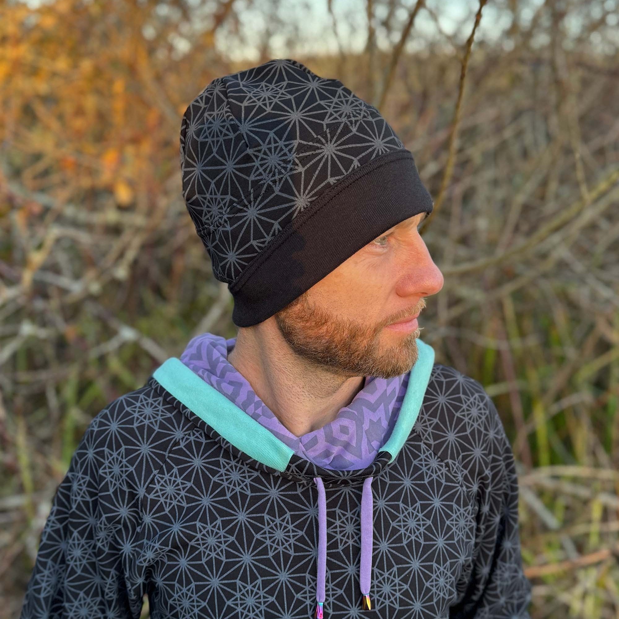 Organic cotton beanie, black fabric with sacred geometry print, right side on male model.