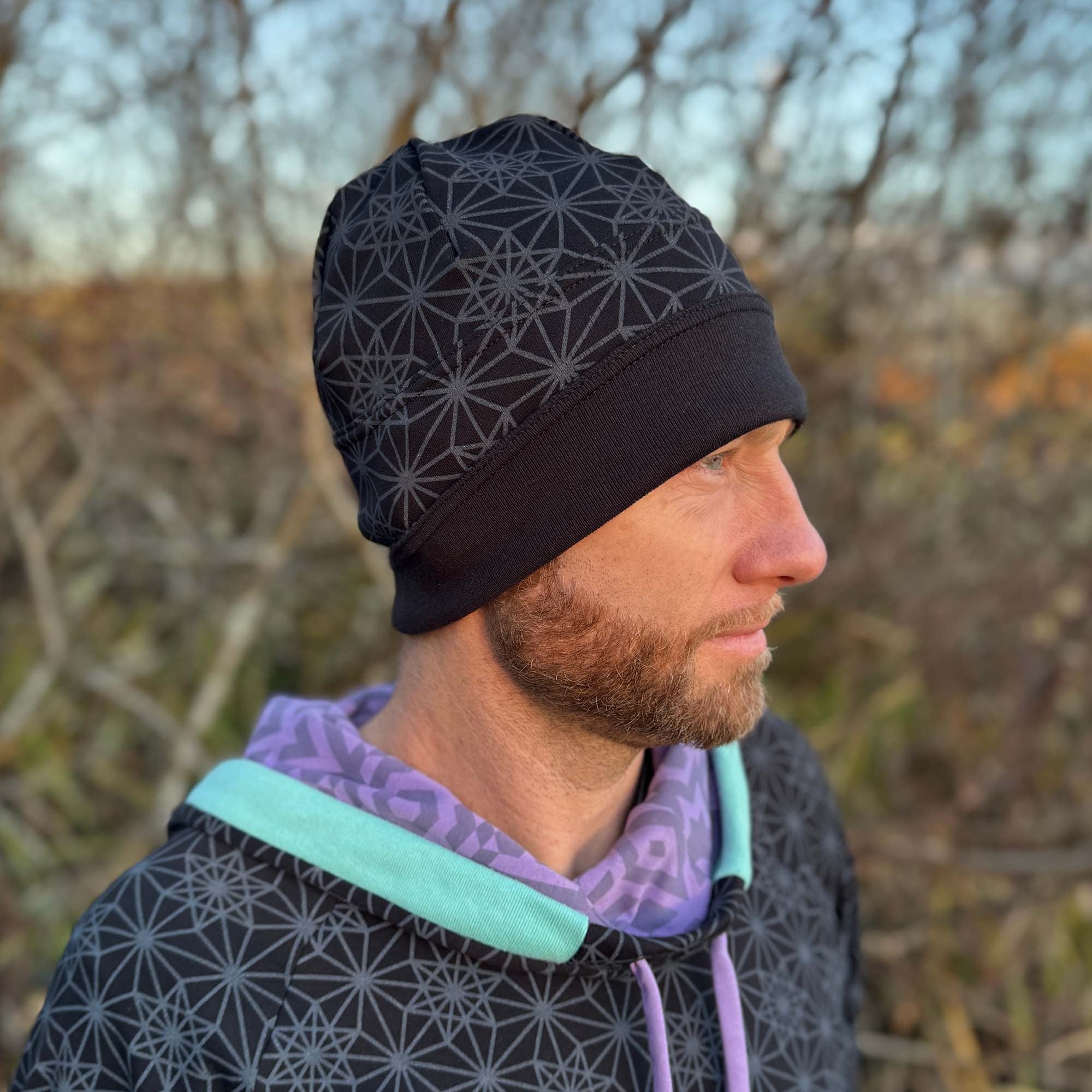 Organic cotton beanie, black fabric with geo print, right side on male model.