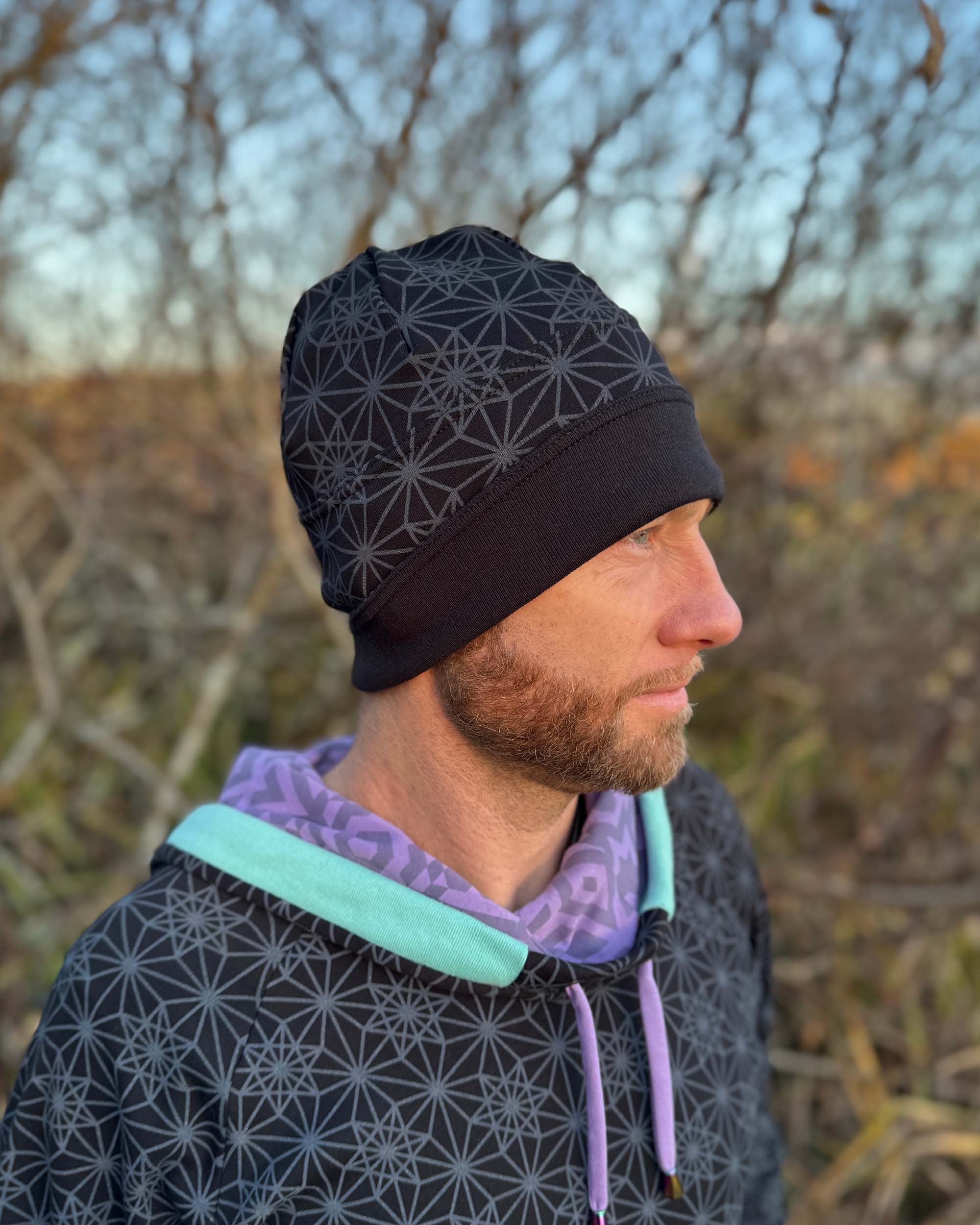 Organic cotton beanie, black fabric with geo print, right side on male model.