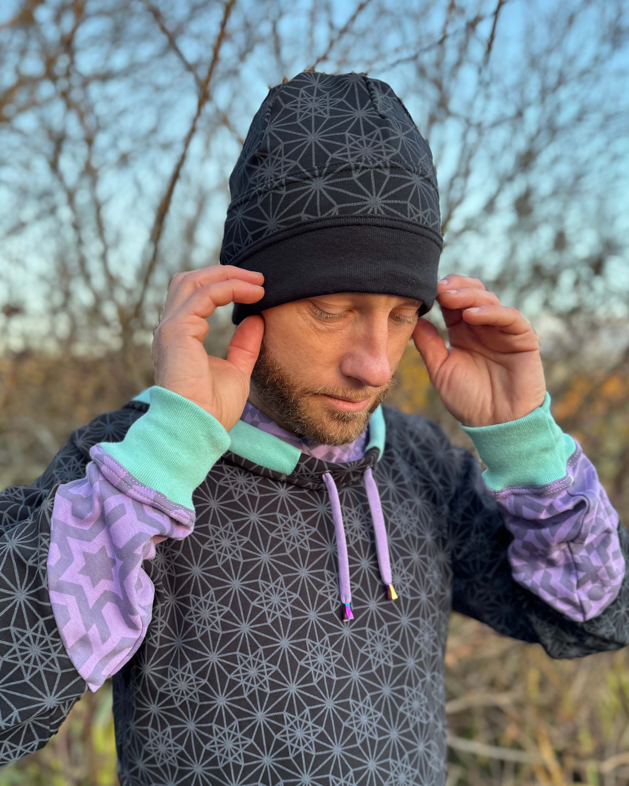 Organic cotton beanie, black fabric with geometric print, front view on male model.