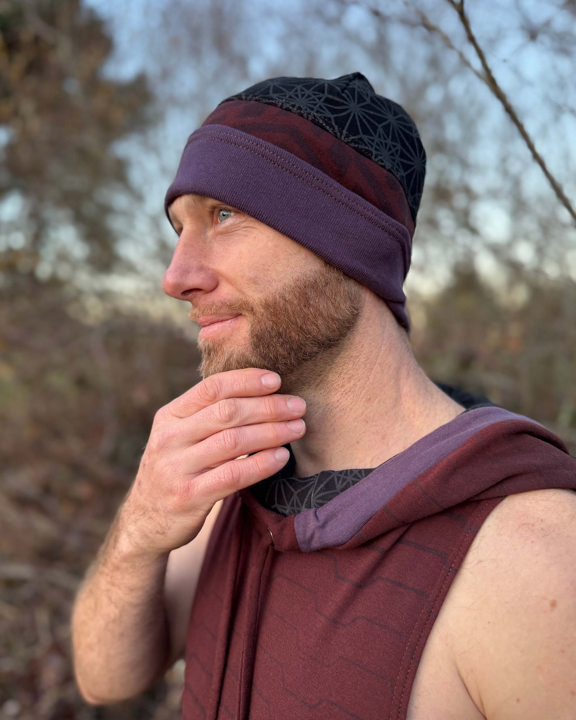 Organic cotton beanie, black and brown with geometric printed fabric, left side view on male model.