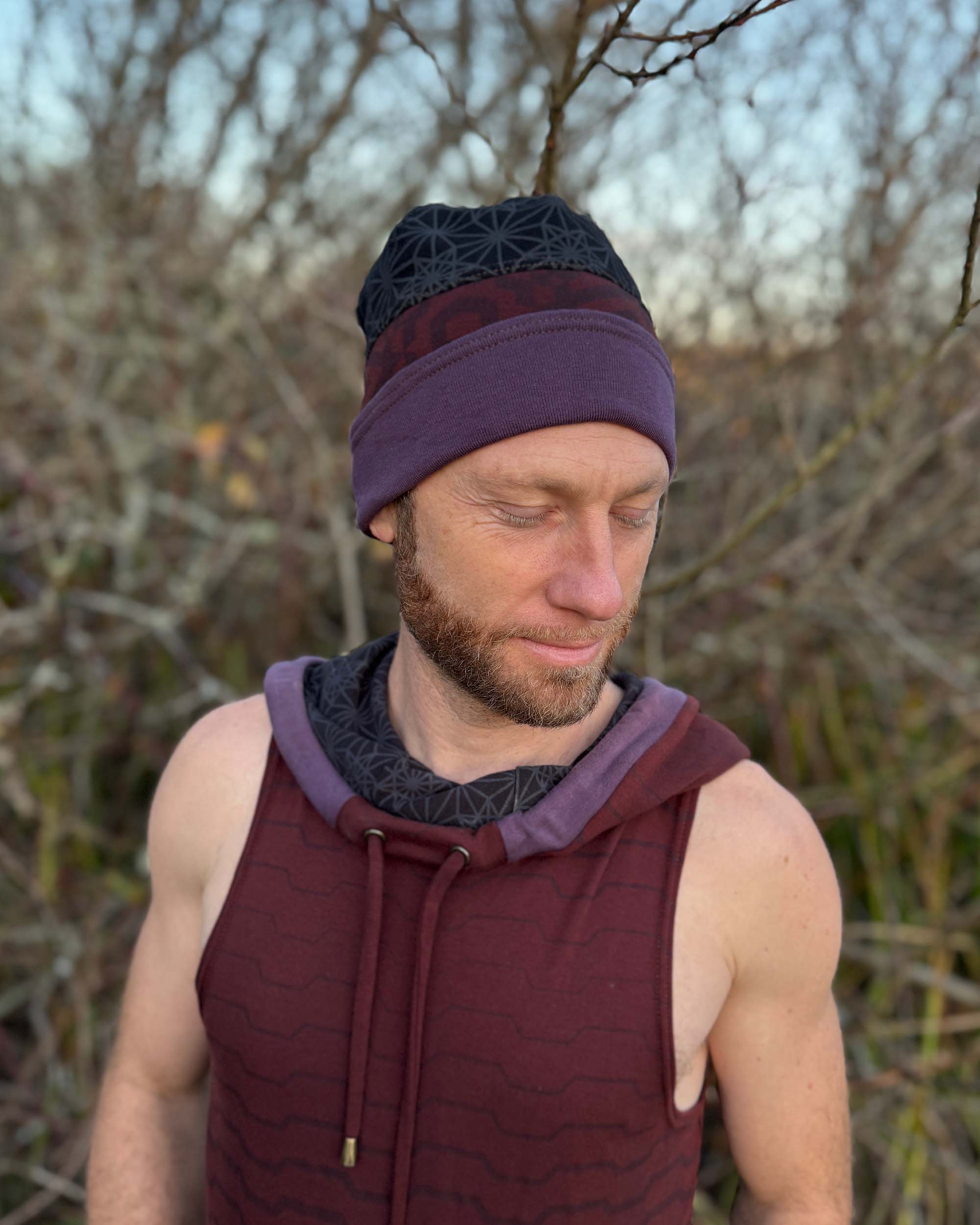 Organic cotton beanie, black and brown with geometric printed fabric, front right side view on male model.