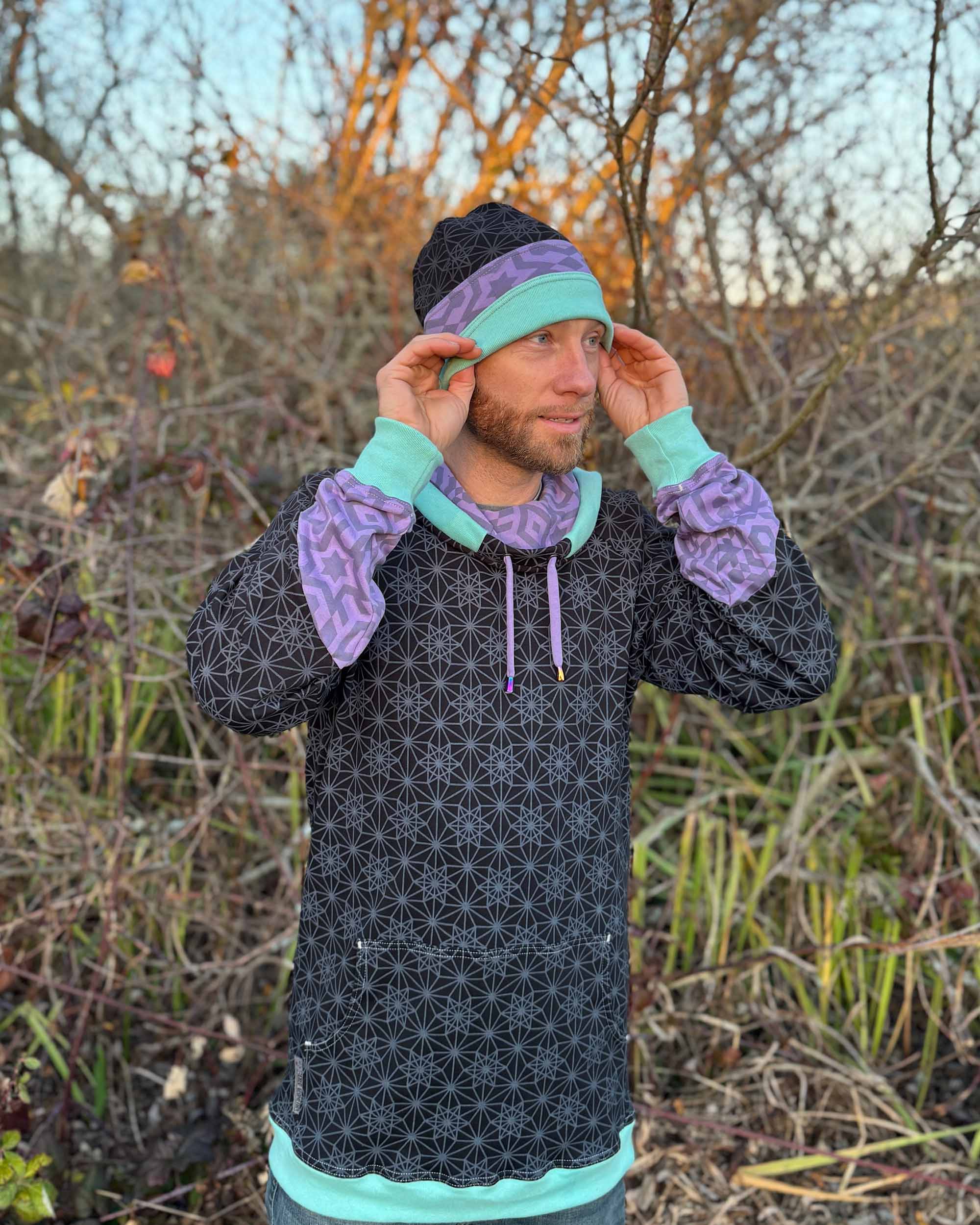Organic cotton beanie, black, lavender and green accent fabric, front right view on male model in nature.
