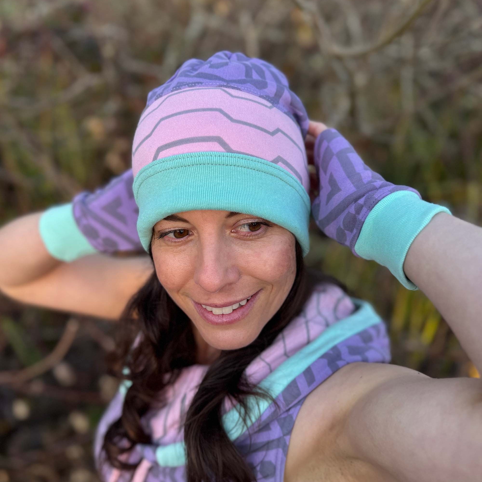 Organic cotton beanie, pink and lavender with geometric printed fabric, front side on female model.