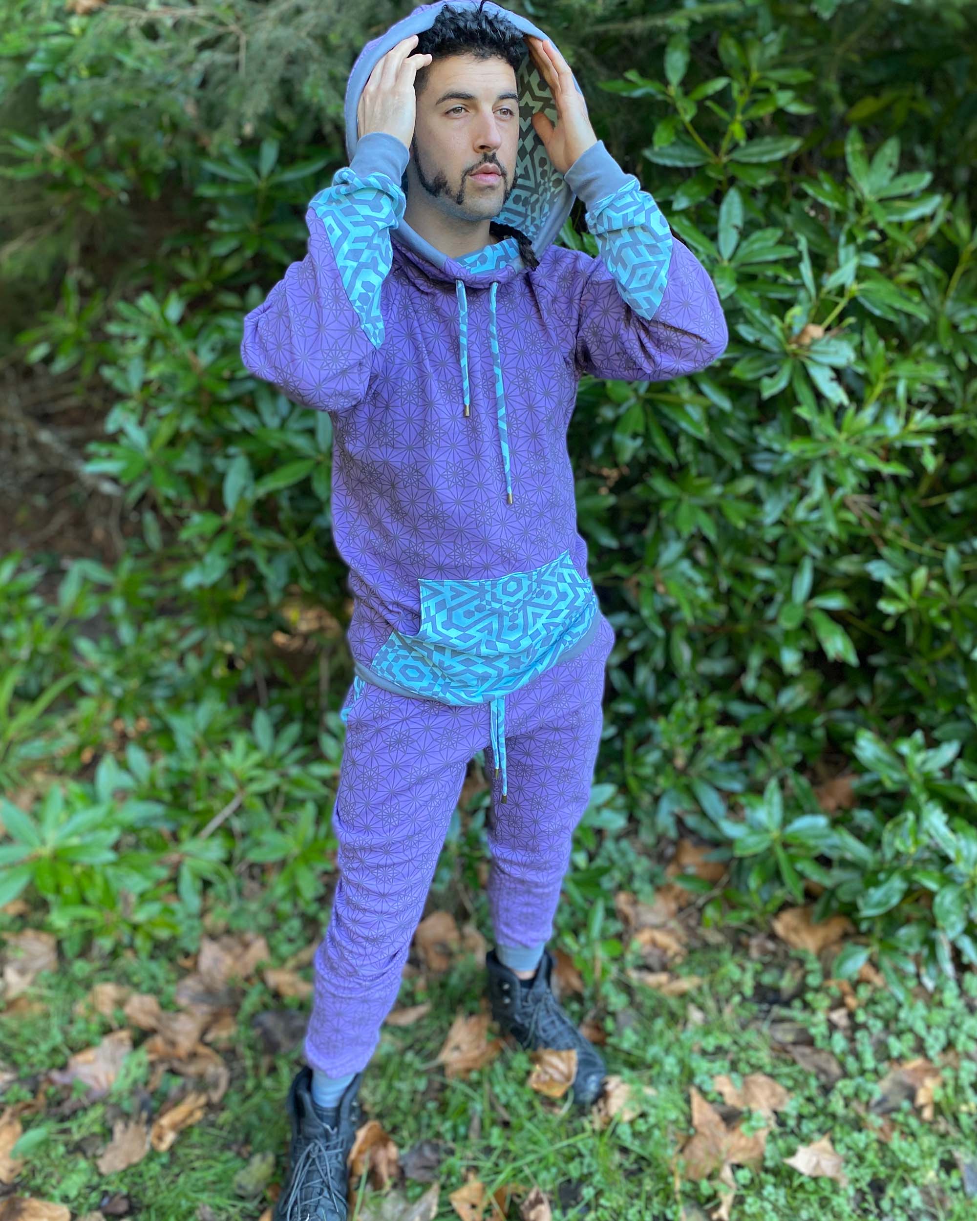 Men's matching two piece sweatsuit, lavender fabric with geometric print, full body view worn by model.