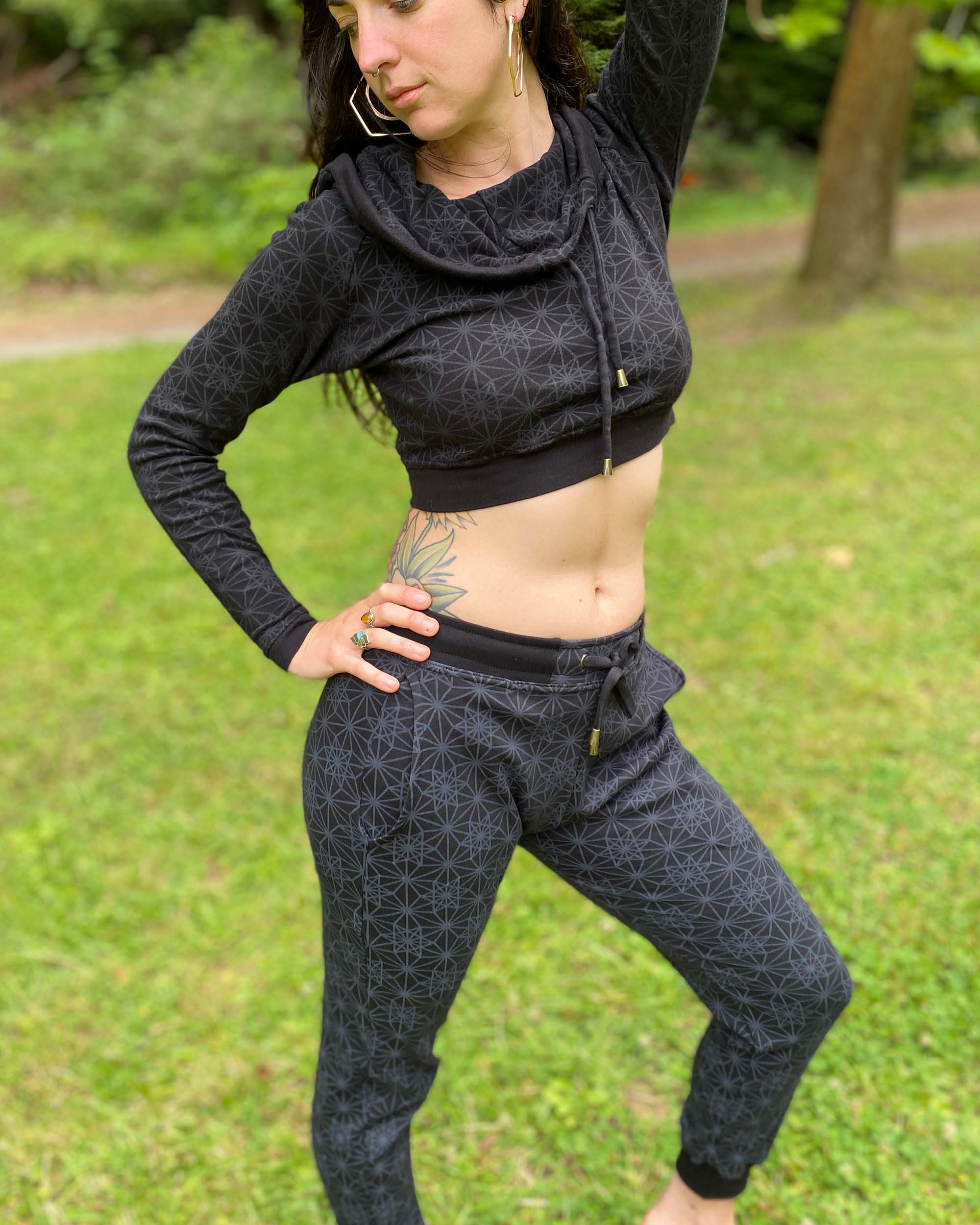 Organic cotton unisex joggers, black fabric with geometric print, full body right side view on female model.