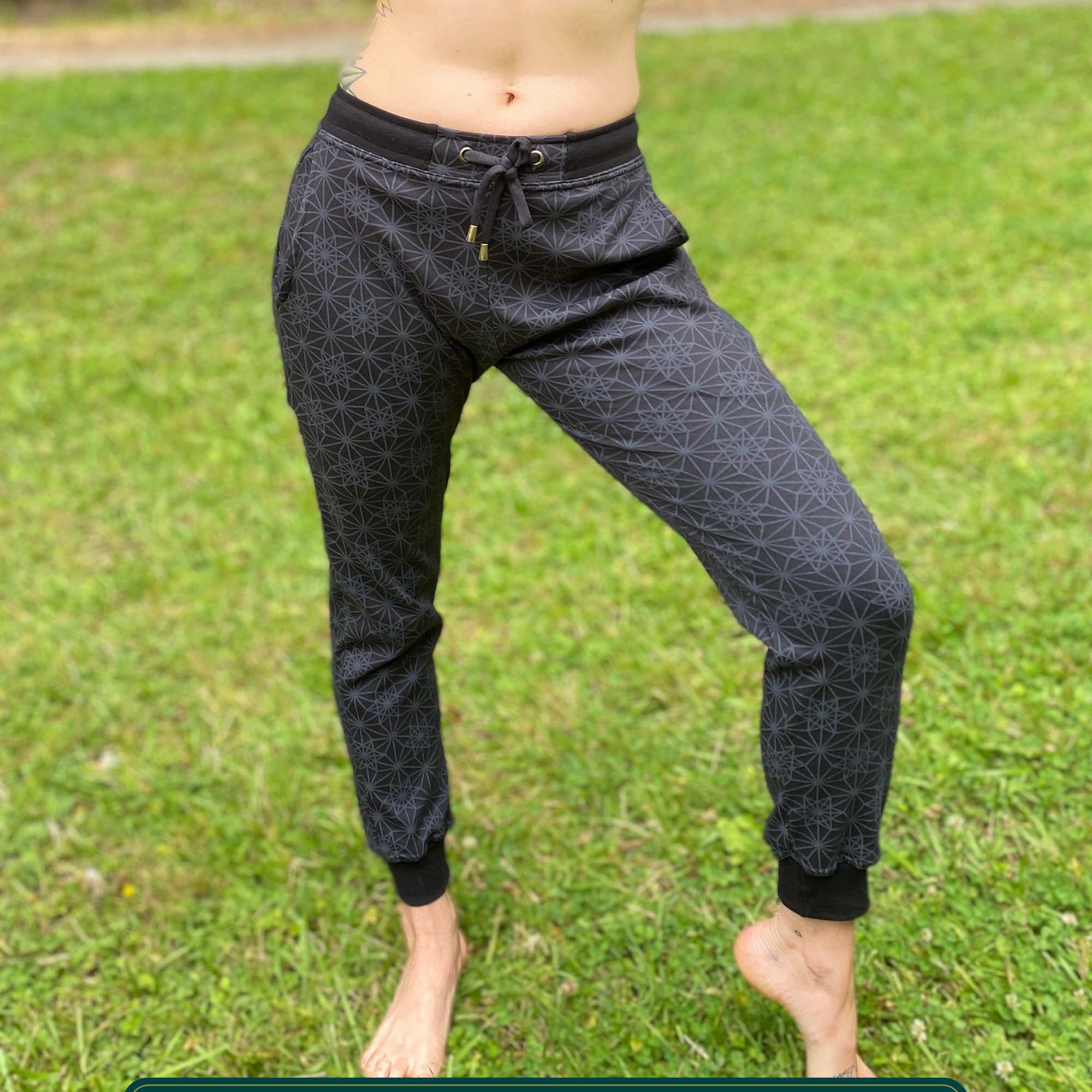 Organic cotton unisex joggers, black fabric with geometric print, front view on female model.