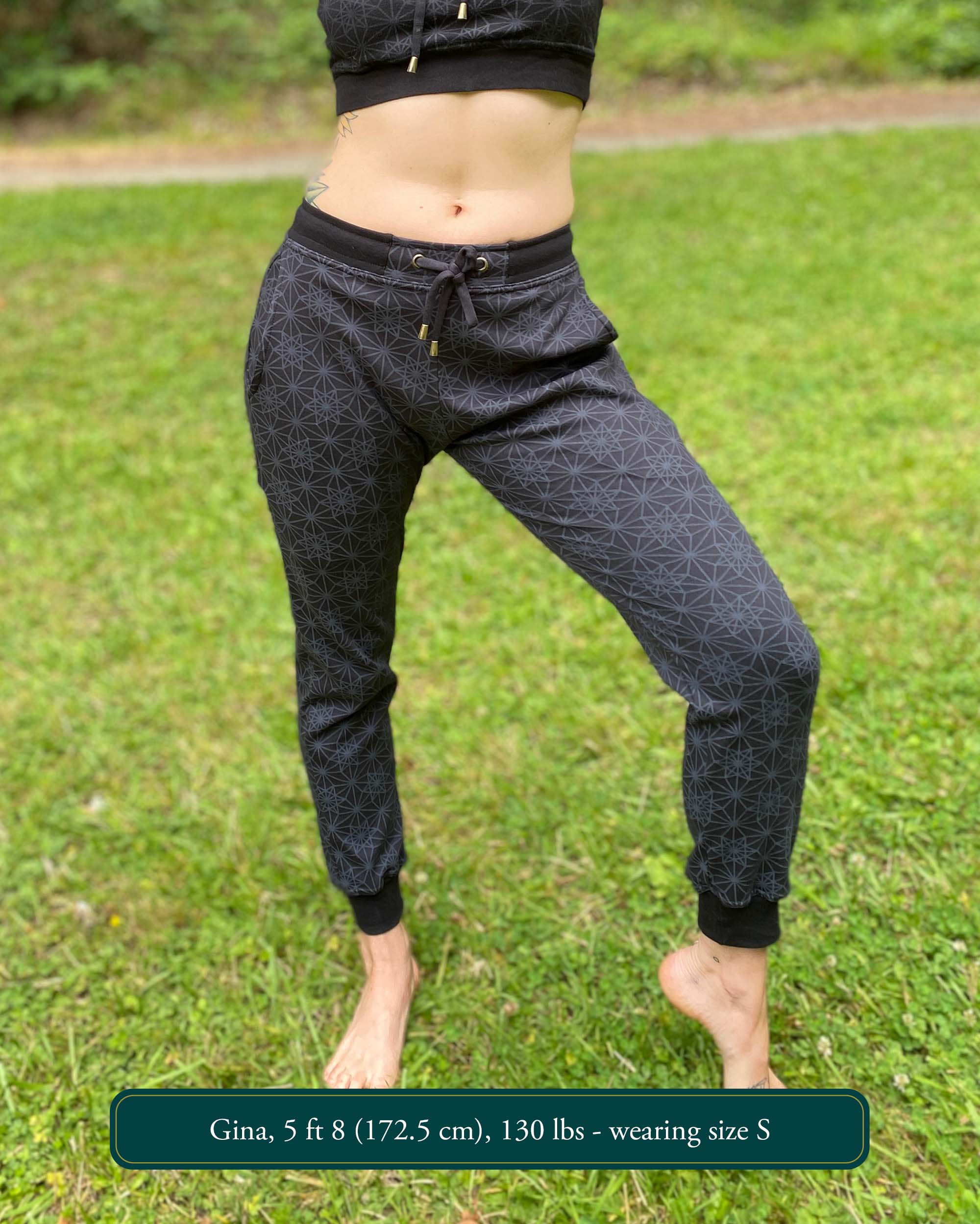 Organic cotton unisex joggers, black fabric with geometric print, front view on female model.