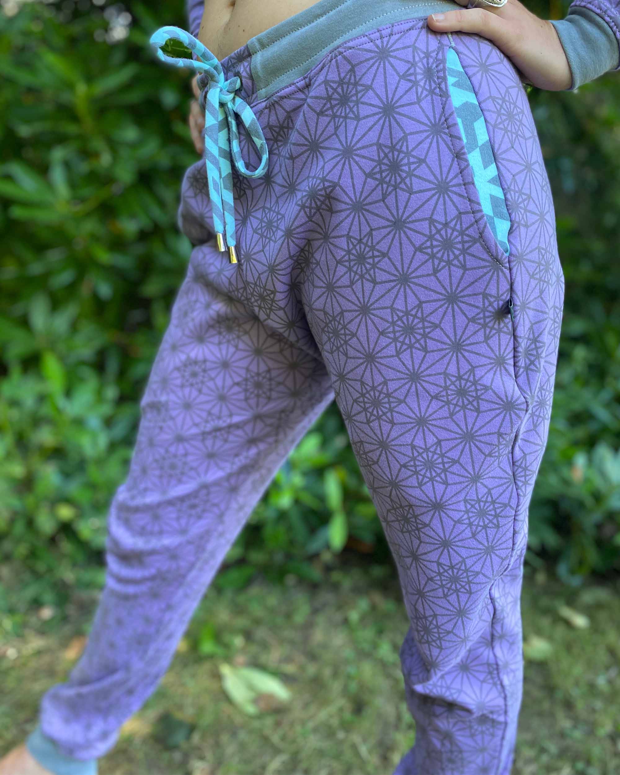 Organic cotton unisex joggers, lavender fabric with geometric print and blue accents, detail view of the drawcord.