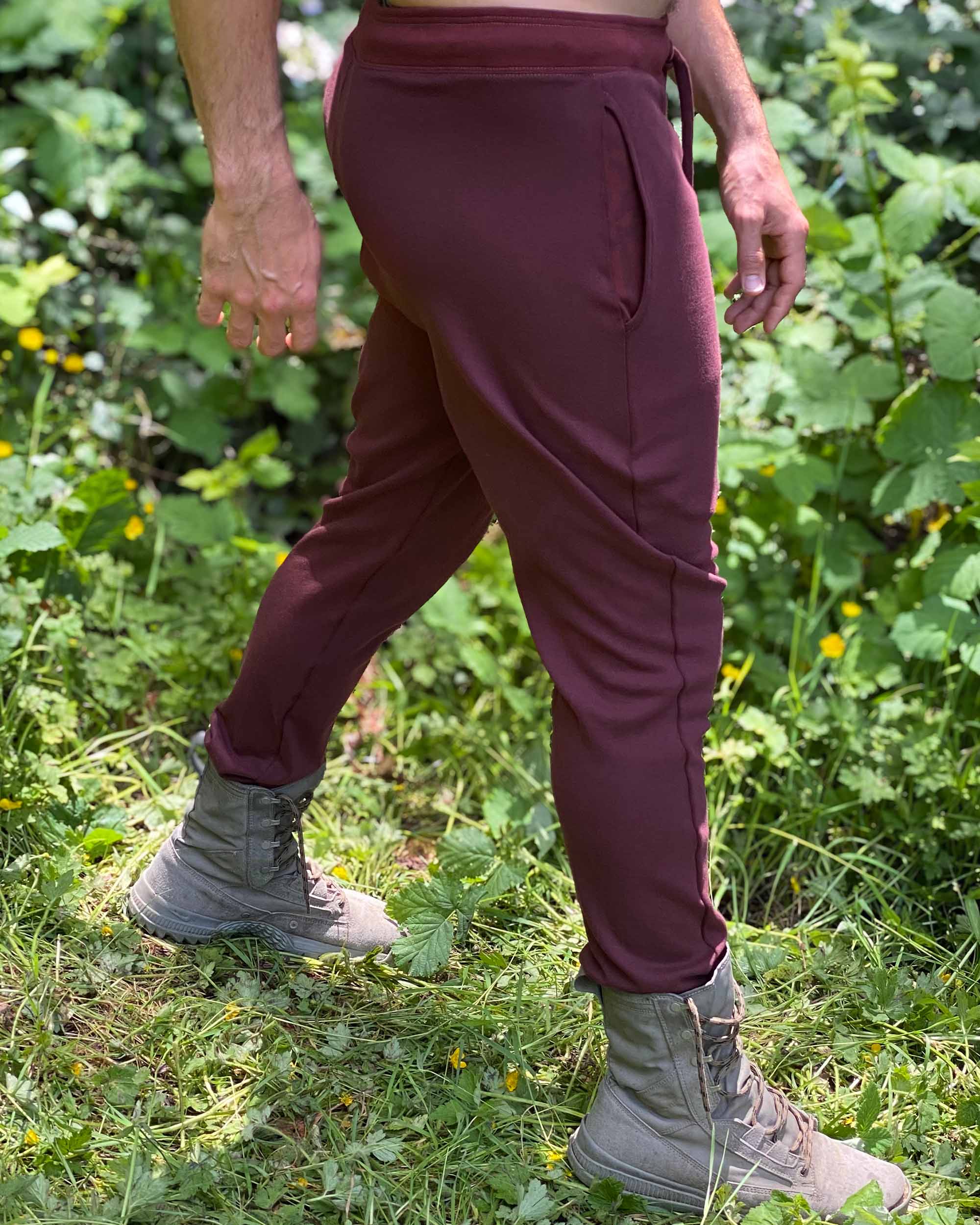 Organic cotton unisex joggers, reddish brown fabric, right side view on male model in nature.