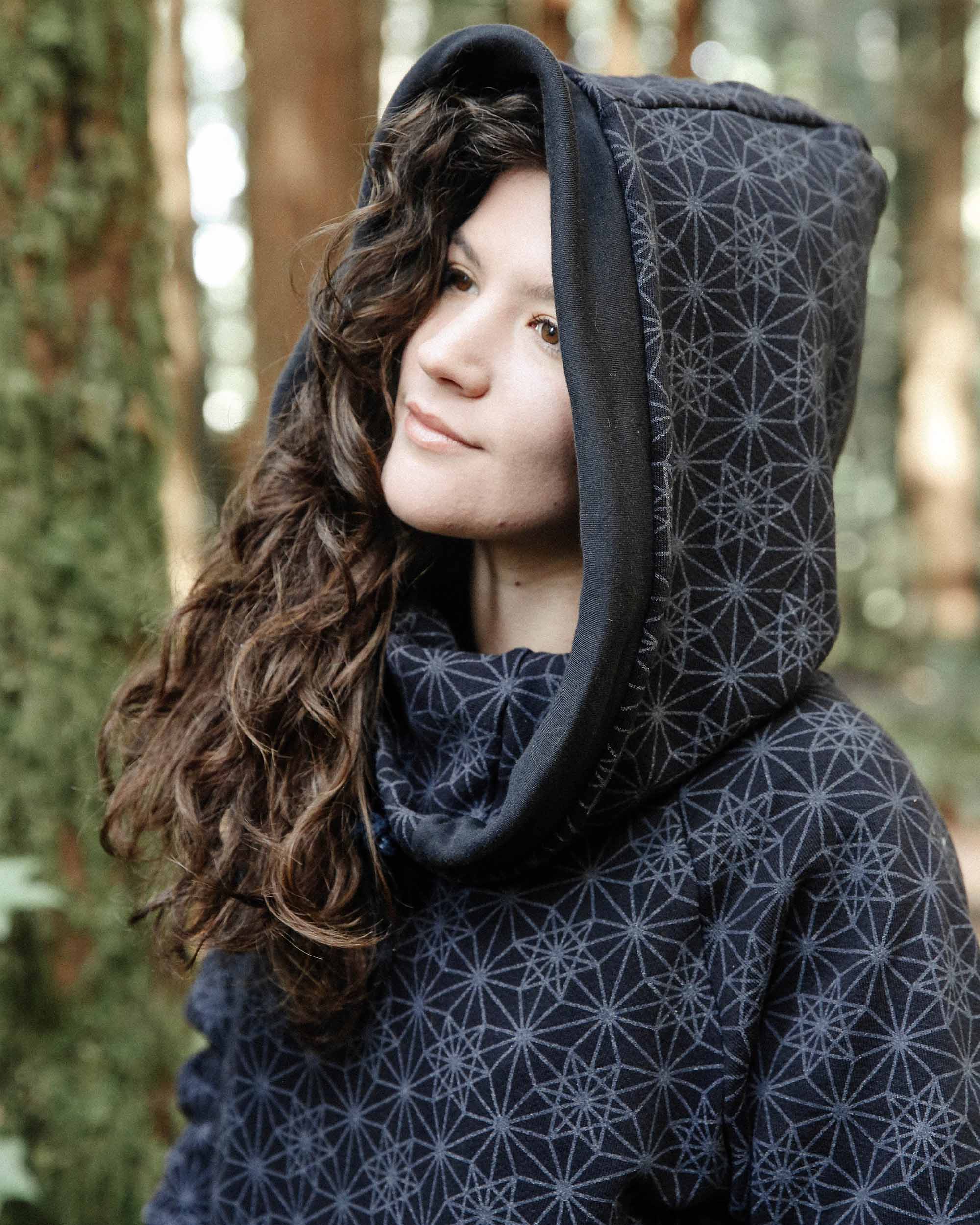 Organic cotton fleece unisex hoodie, black fabric with geometric print, left side close up view of hood.