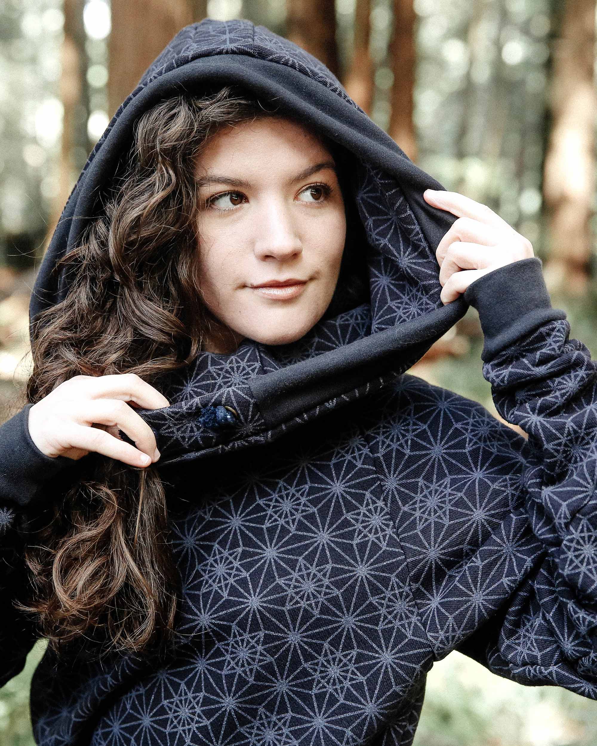 Organic cotton fleece unisex hoodie, black fabric with geometric print, close up view of hood.