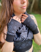Organic cotton hand warmers and matching scarf in black fabric and geometric print, right side view on female model.