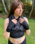Organic cotton hand warmers and matching scarf in black fabric and geometric print, front view on female model.