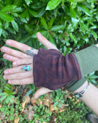Organic cotton fingerless gloves in reddish brown colored fabric with geometric print, top view.