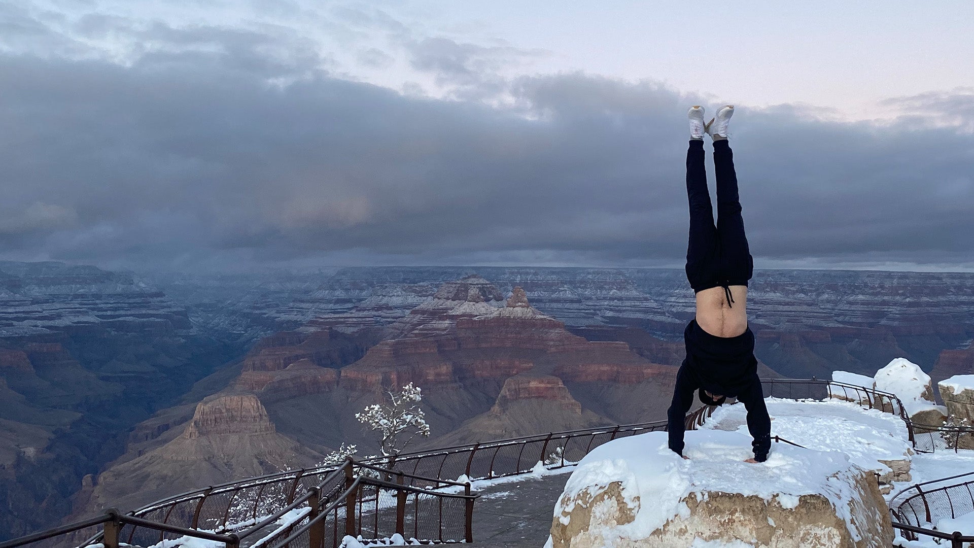 Male doing a handstand at snow covered Grand Canyon, wearing organic cotton black joggers.