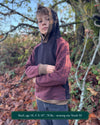 Organic cotton youth fleece hoodie, black and brown color with geometric printed sleeves, worn by a boy in nature.