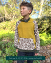 Organic cotton youth fleece hoodie, yellow  with geometric printed sleeves, front view, worn by a boy in nature.