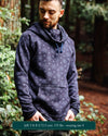 Organic cotton fleece unisex hoodie, black fabric with geometric print, front right view on male model in nature.