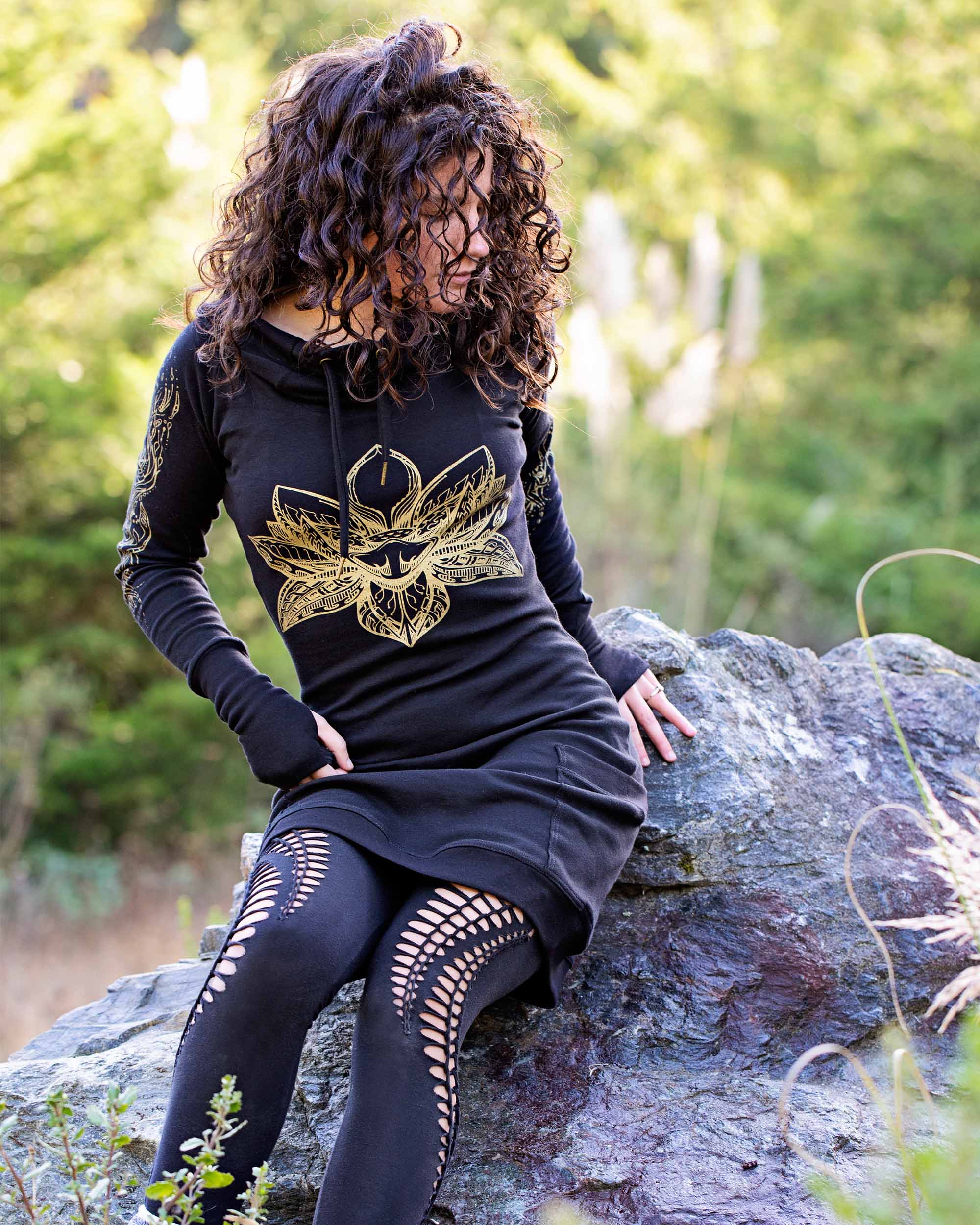 Organic cotton long sleeve tunic dress, black with front gold lotus print, full length front view of sitting female model.