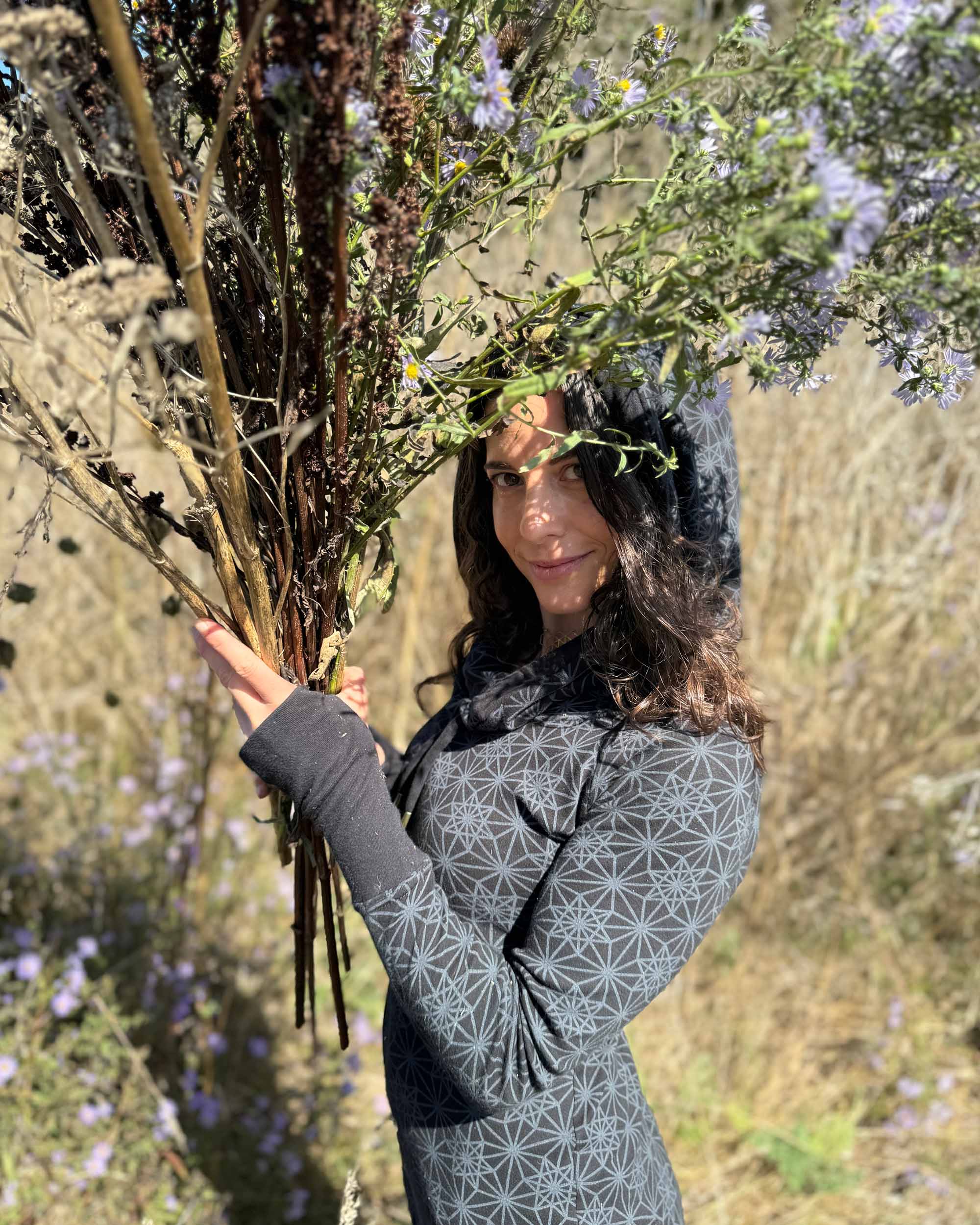 Organic cotton long sleeve tunic dress, black with sacred geometry print, left side view on female model.