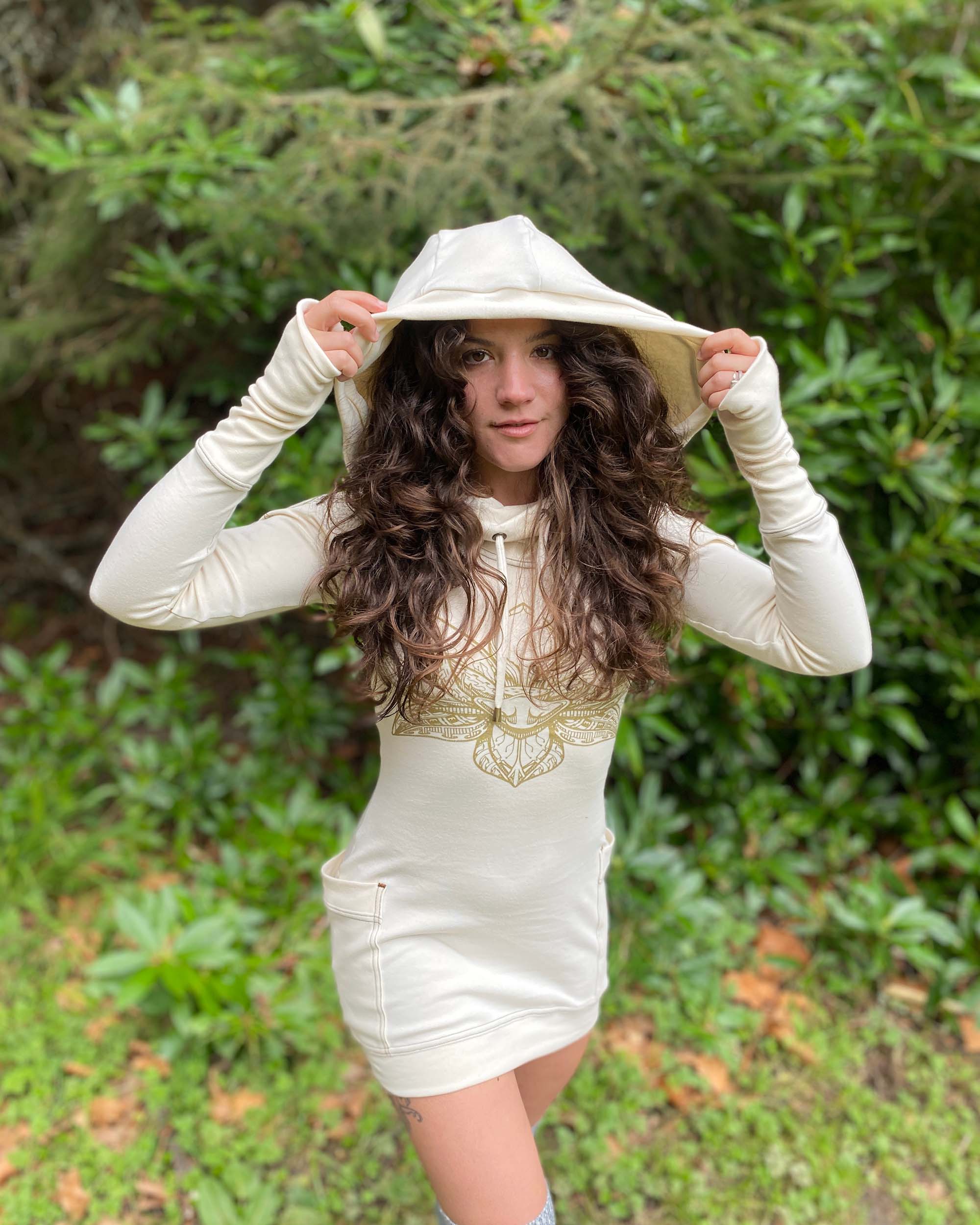 Organic cotton long sleeve tunic dress, undyed fabric with front gold lotus print, worn by female model with hood up.