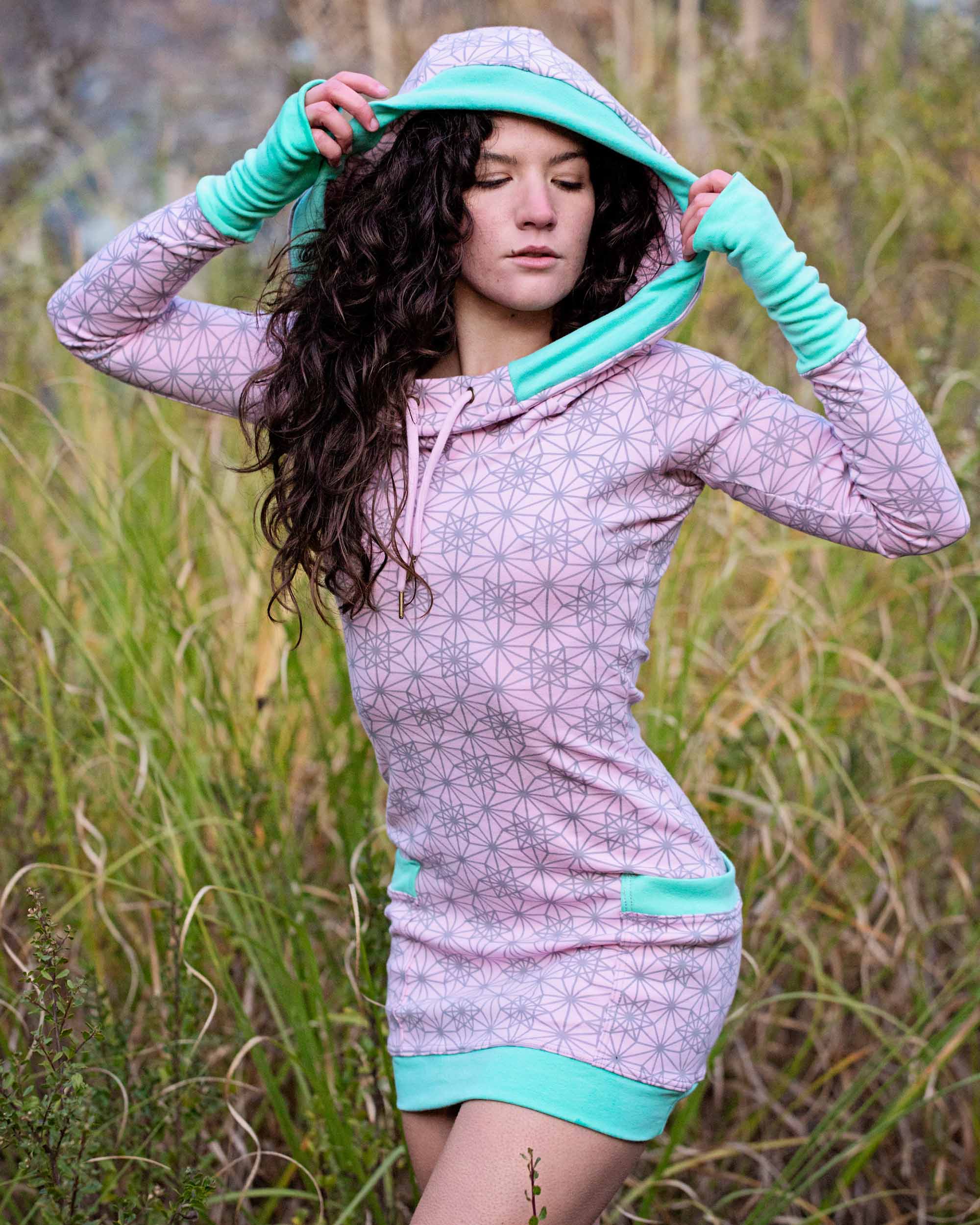 Organic cotton fitted tunic dress, pink fabric with geometric print, front view on female model.