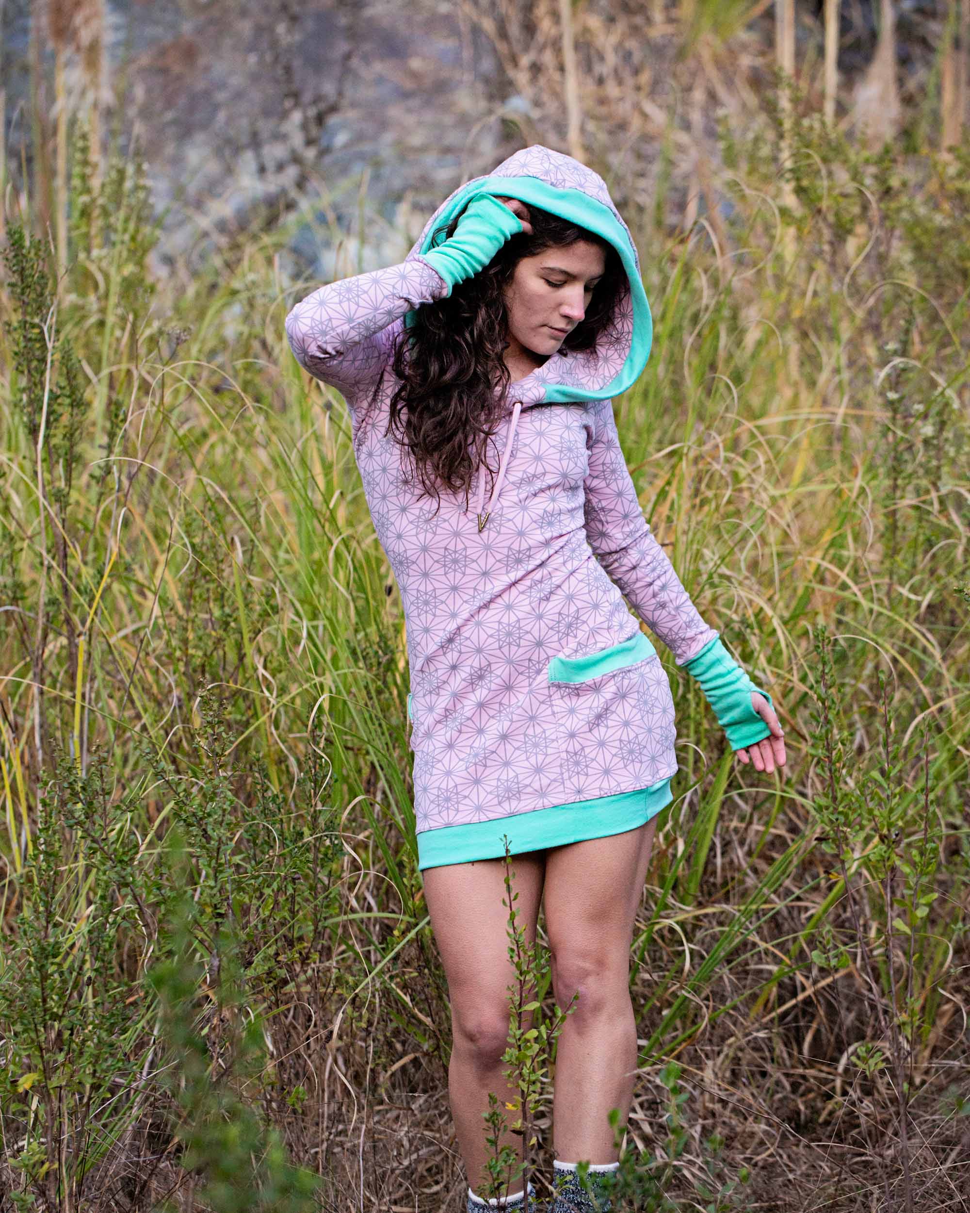 Organic cotton fitted tunic dress, pink with green accent fabric, front view on female model in nature.