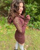 Organic cotton long sleeve tunic dress, brown with front gold lotus print, right side view on female model.