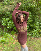 Organic cotton long sleeve tunic dress, brown fabric with front gold lotus print, worn by female model.