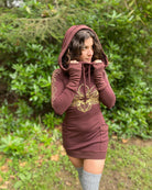 Organic cotton long sleeve tunic dress, brown fabric with front gold lotus print, worn by female model in nature.