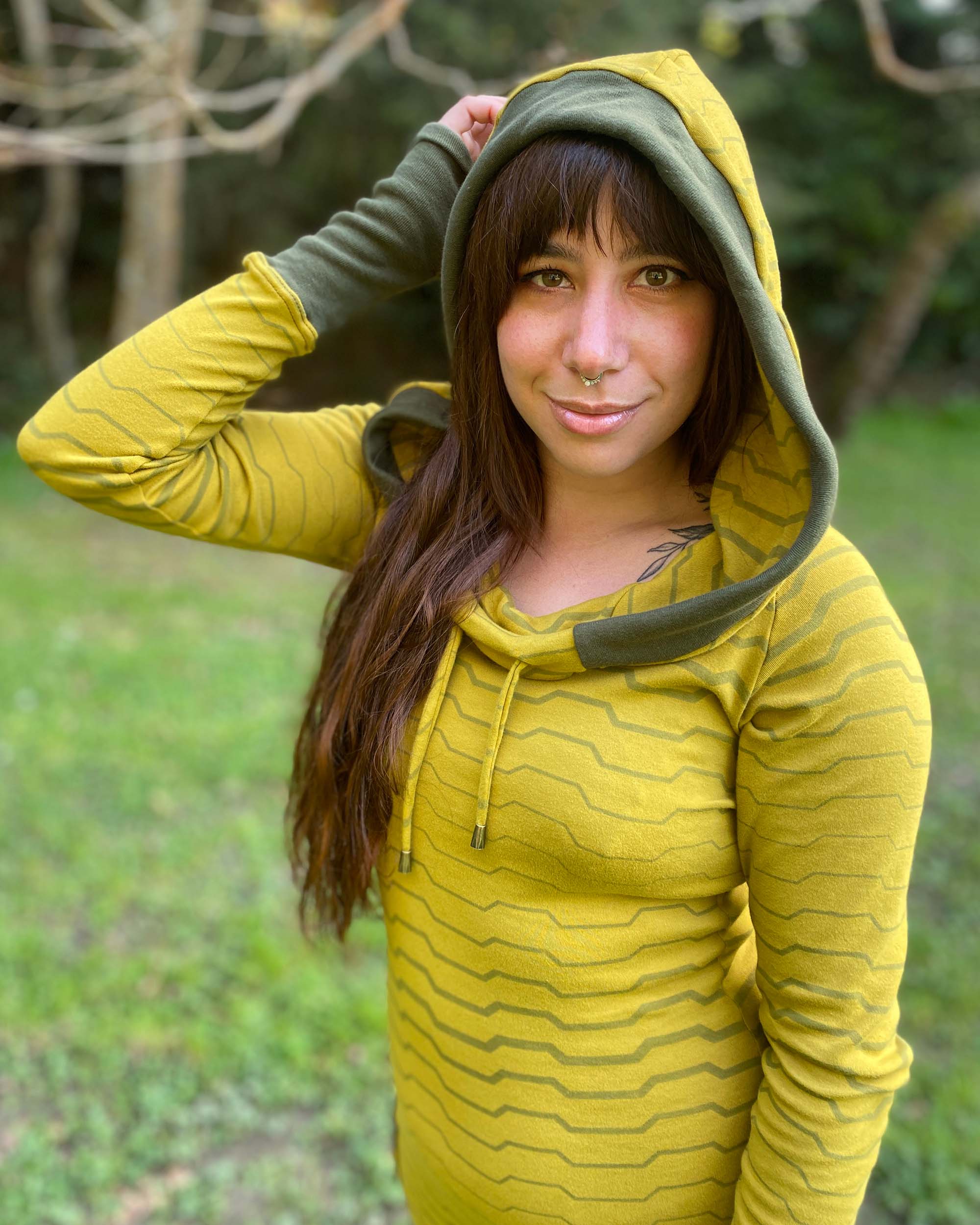 Organic cotton long sleeve tunic dress, yellow with green accent fabric, front view on female model with hood up.