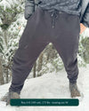 Organic cotton fleece joggers, solid black fabric, front view on male model in the snow.