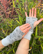 Hands wearing organic cotton hand warmers, grey fabric with geometric print.