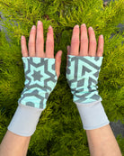 Female hands wearing organic cotton hand warmers, mint colored geo printed fabric.