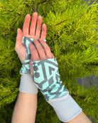 Hands wearing organic cotton hand warmers, mint colored geo printed fabric.