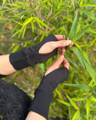 female hands wearing organic cotton wrist warmers with black fabric and natural background.