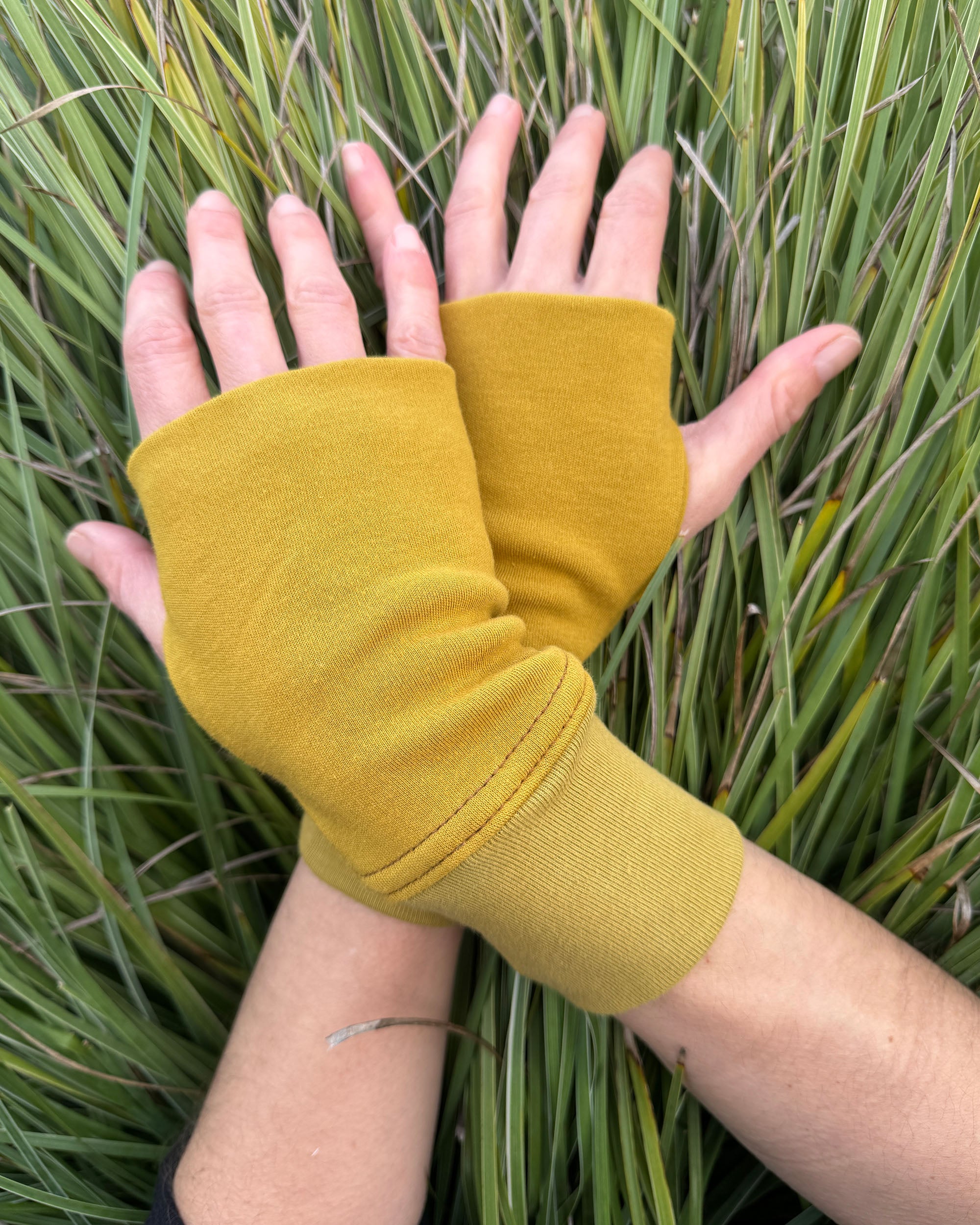 Organic cotton hand warmers, yellow solid fabric with natural background.