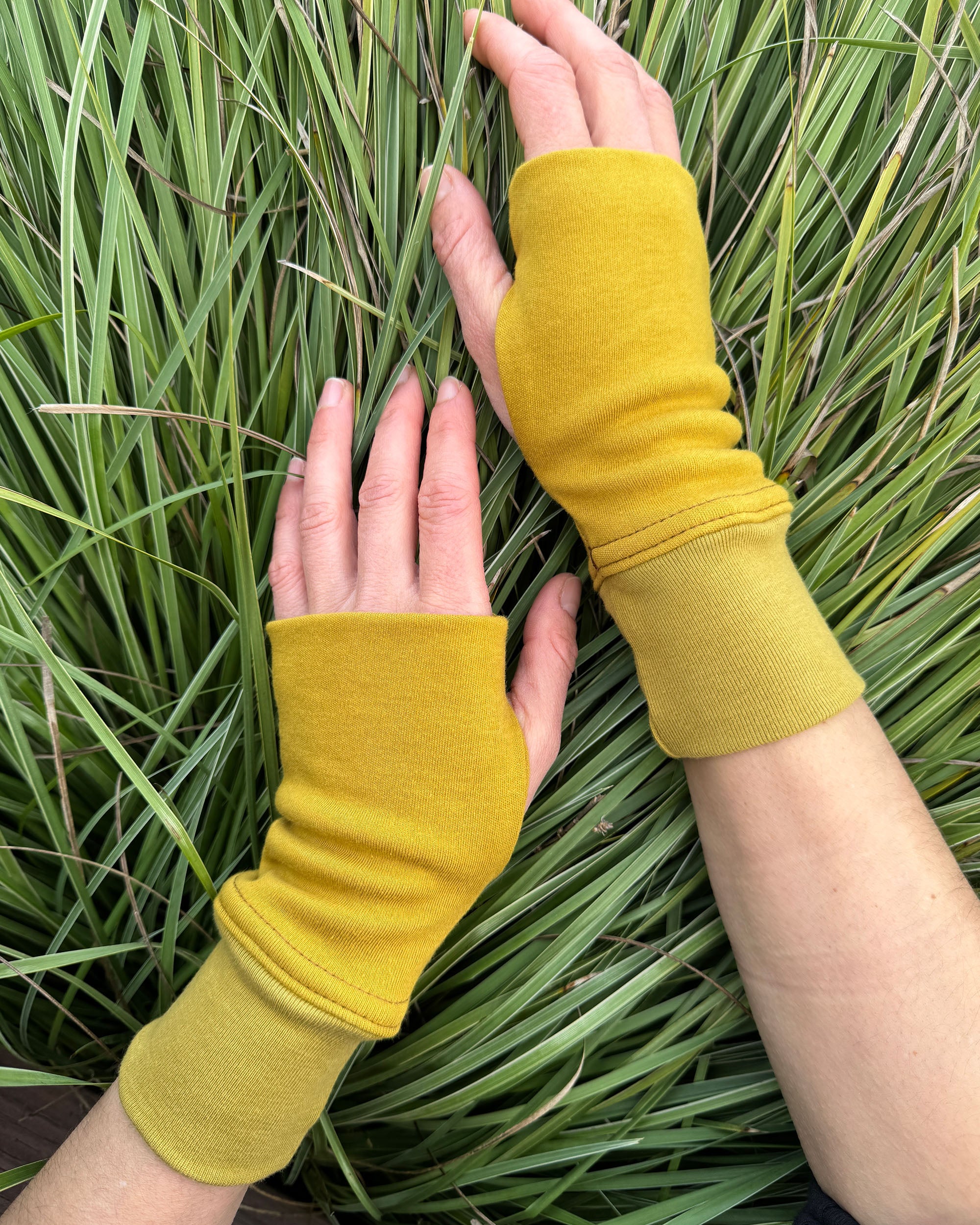 Organic cotton hand warmers, mustard solid fabric with grassy background.