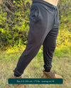Organic cotton joggers, black fabric, right side full body view on male model in nature.
