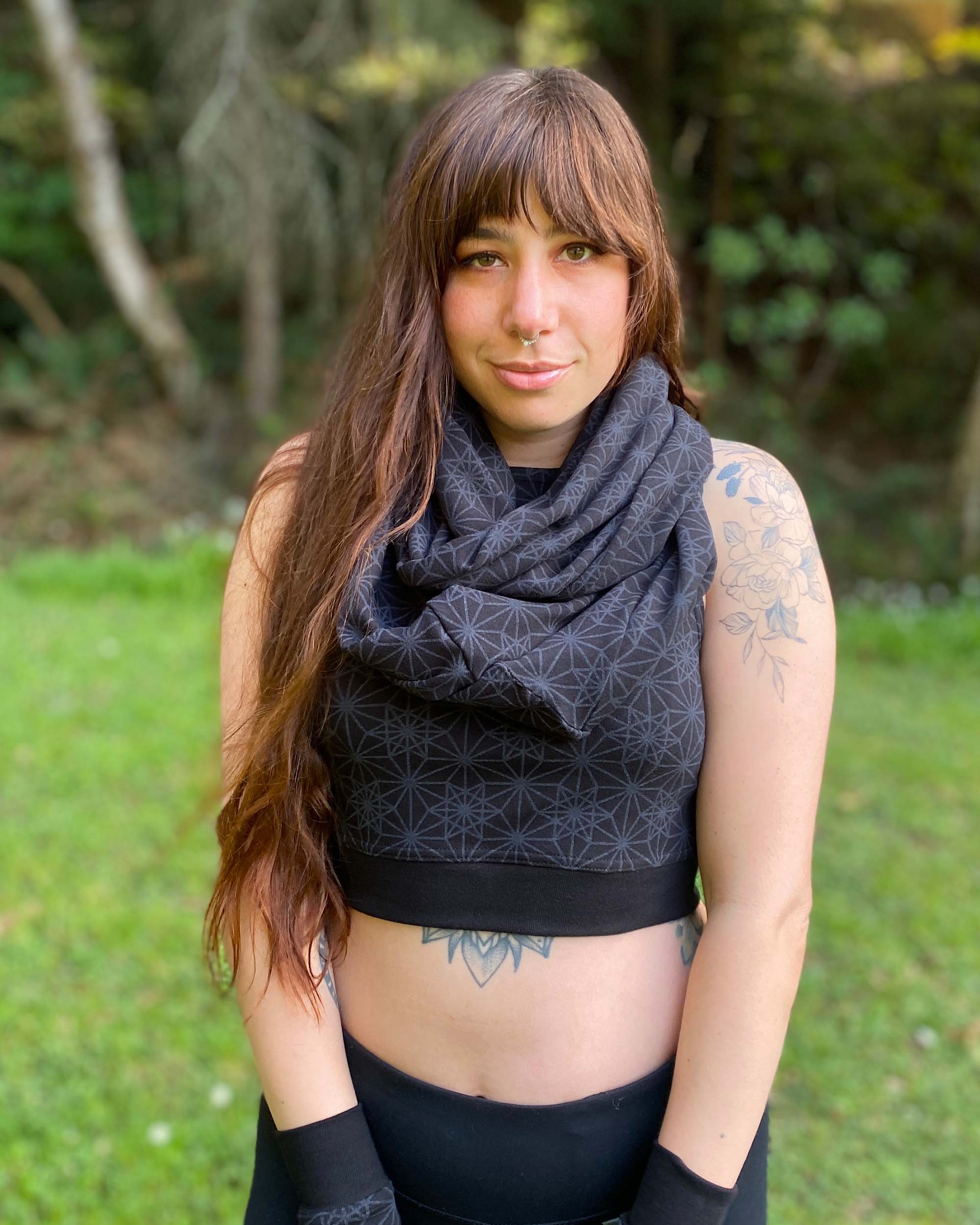 Organic cotton infinity scarf, black fabric with sacred geometry print, front view on female model. 