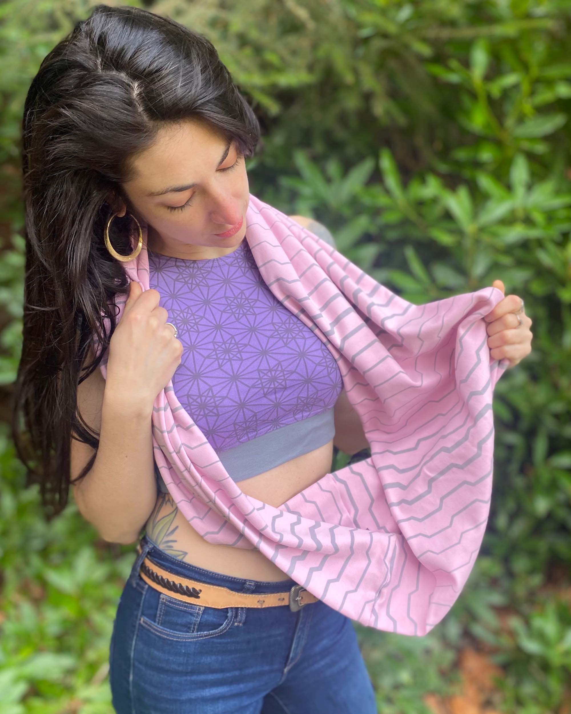 Organic cotton infinity scarf, pink fabric with geometric stripes, front right side view on female model. 