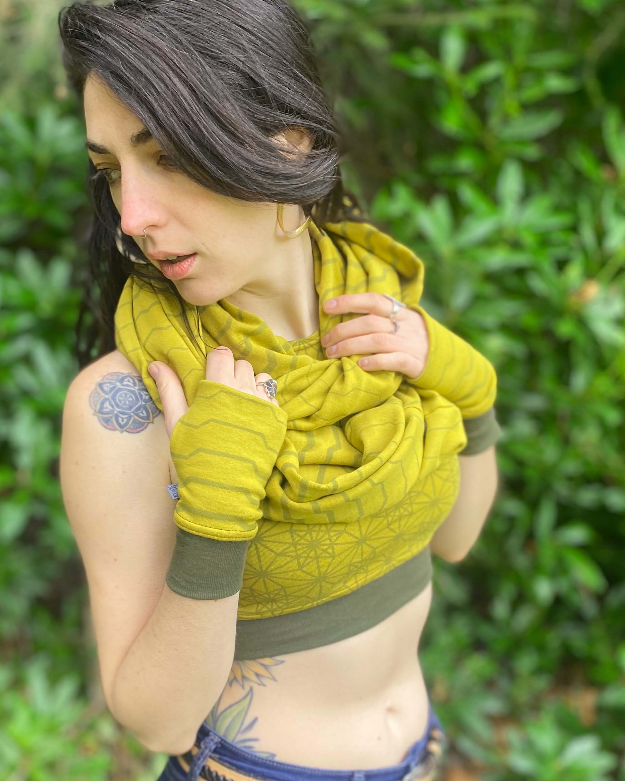 Organic cotton infinity scarf, yellow fabric with geometric stripes, right front view on female model. 