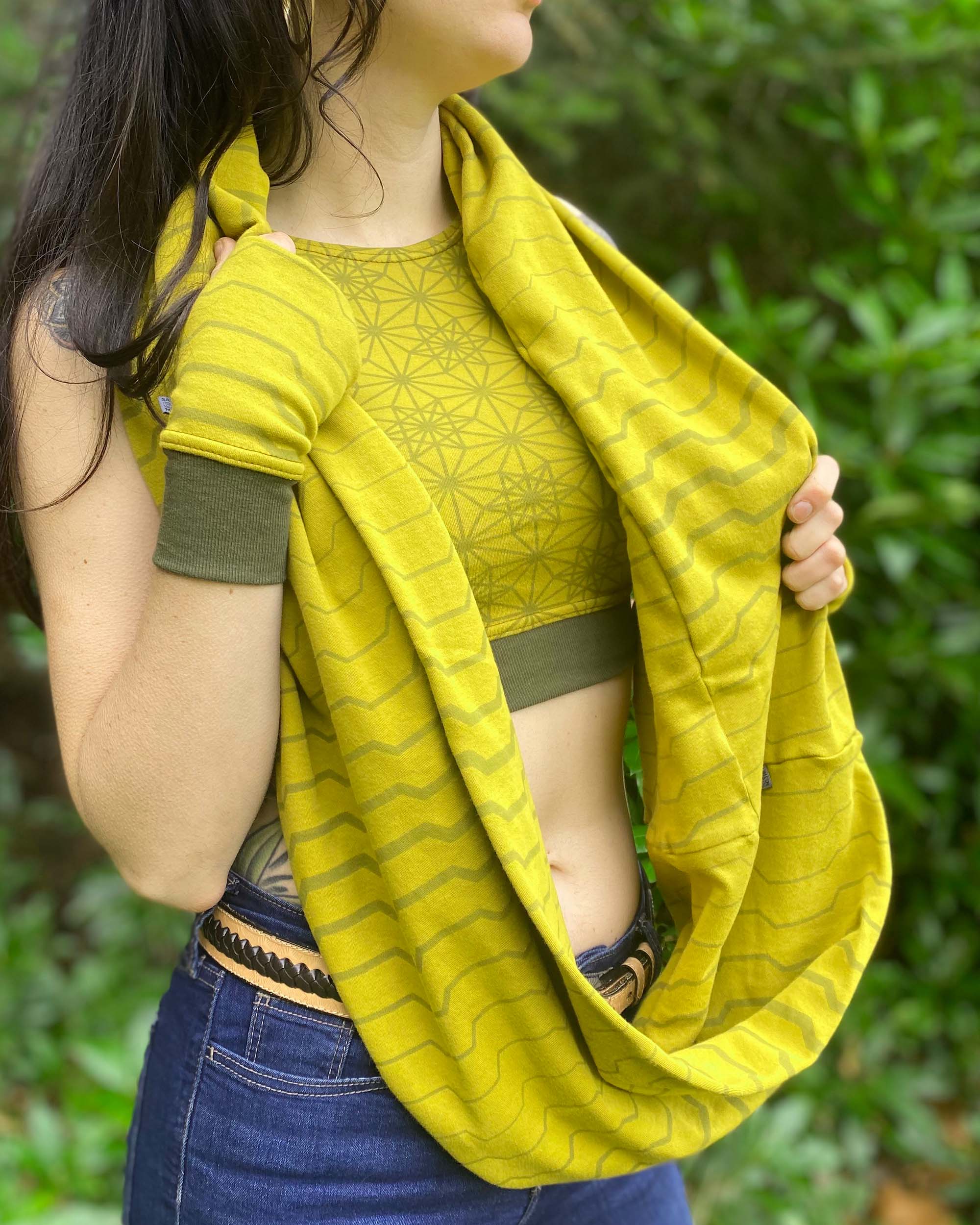 Organic cotton infinity scarf, yellow fabric with geometry print, right front view on female model. 