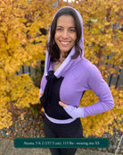 Fitted crop hoodie with cowl hood, black fabric with lavender accent, left side view on model.